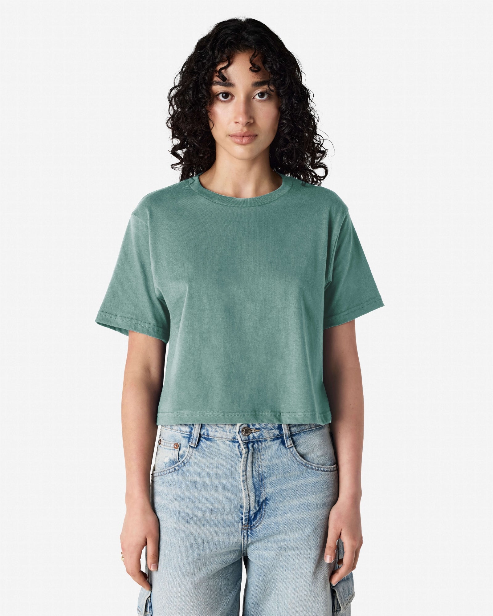 Female model wearing an American Apparel Fine Jersey Women's Boxy Tee in arctic, paired with blue jeans, standing against a plain background (front pose) -arctic