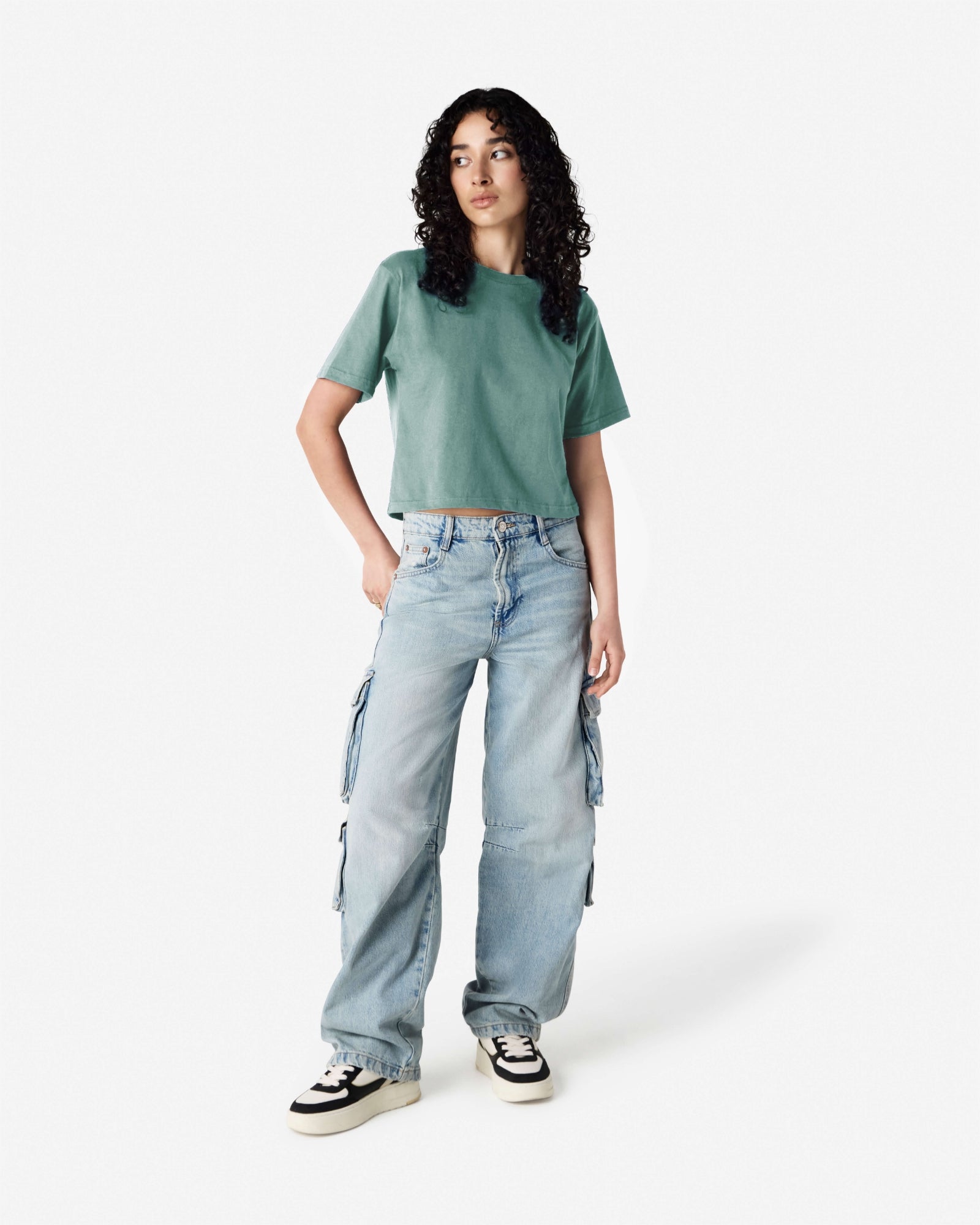 Female model wearing an American Apparel Fine Jersey Women's Boxy Tee in arctic, paired with blue jeans, standing against a plain background (front pose) -arctic