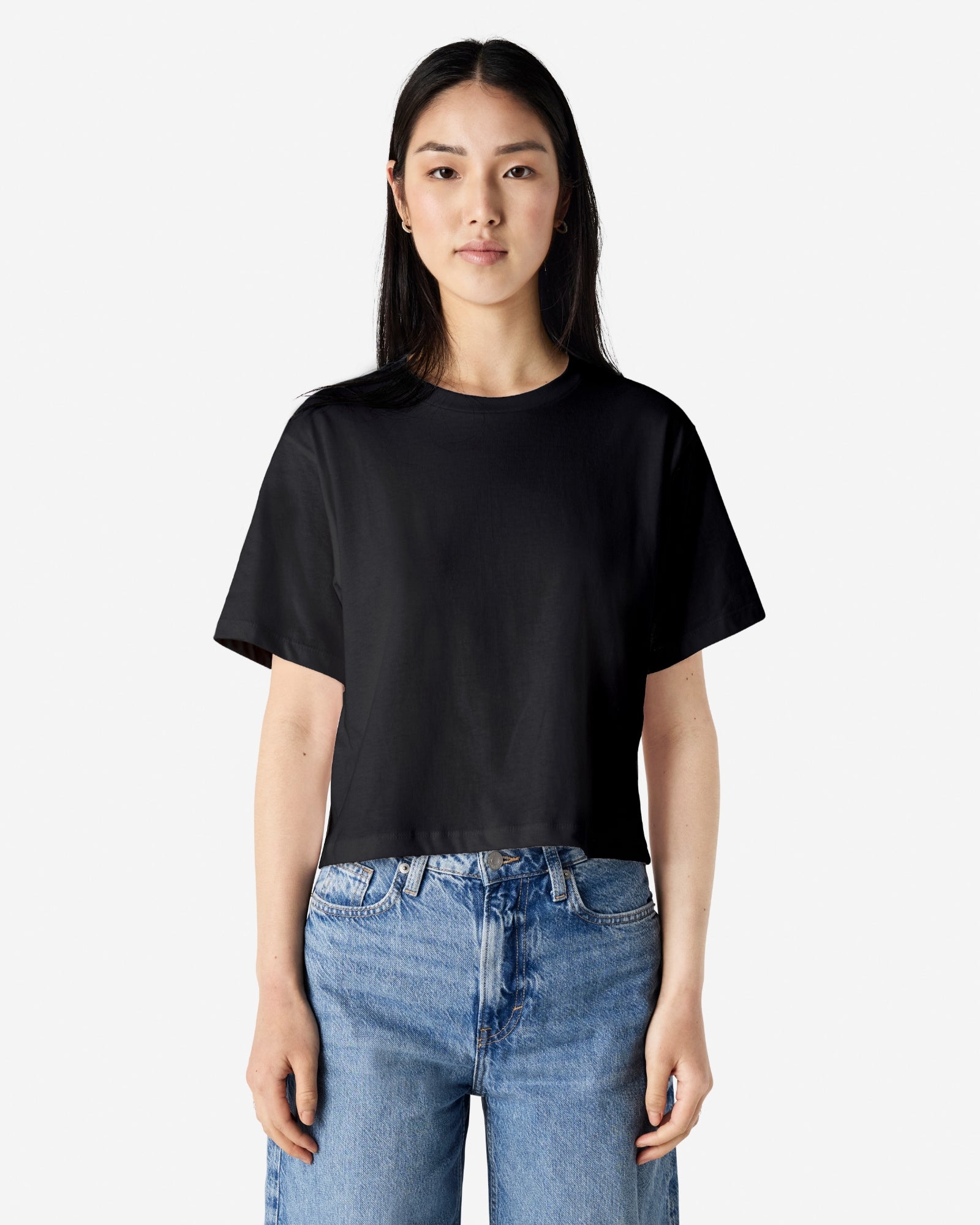 Female model wearing an American Apparel Fine Jersey Women's Boxy Tee in Black, paired with blue jeans, standing against a plain background (front pose) -black