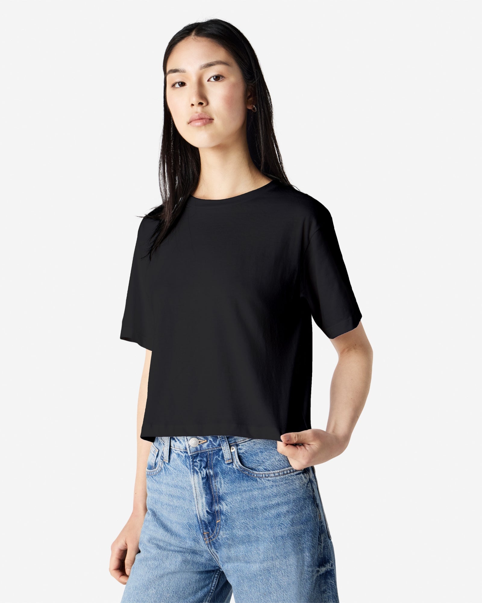 Female model wearing an American Apparel Fine Jersey Women's Boxy Tee in Black, paired with blue jeans, standing against a plain background (front pose) -black