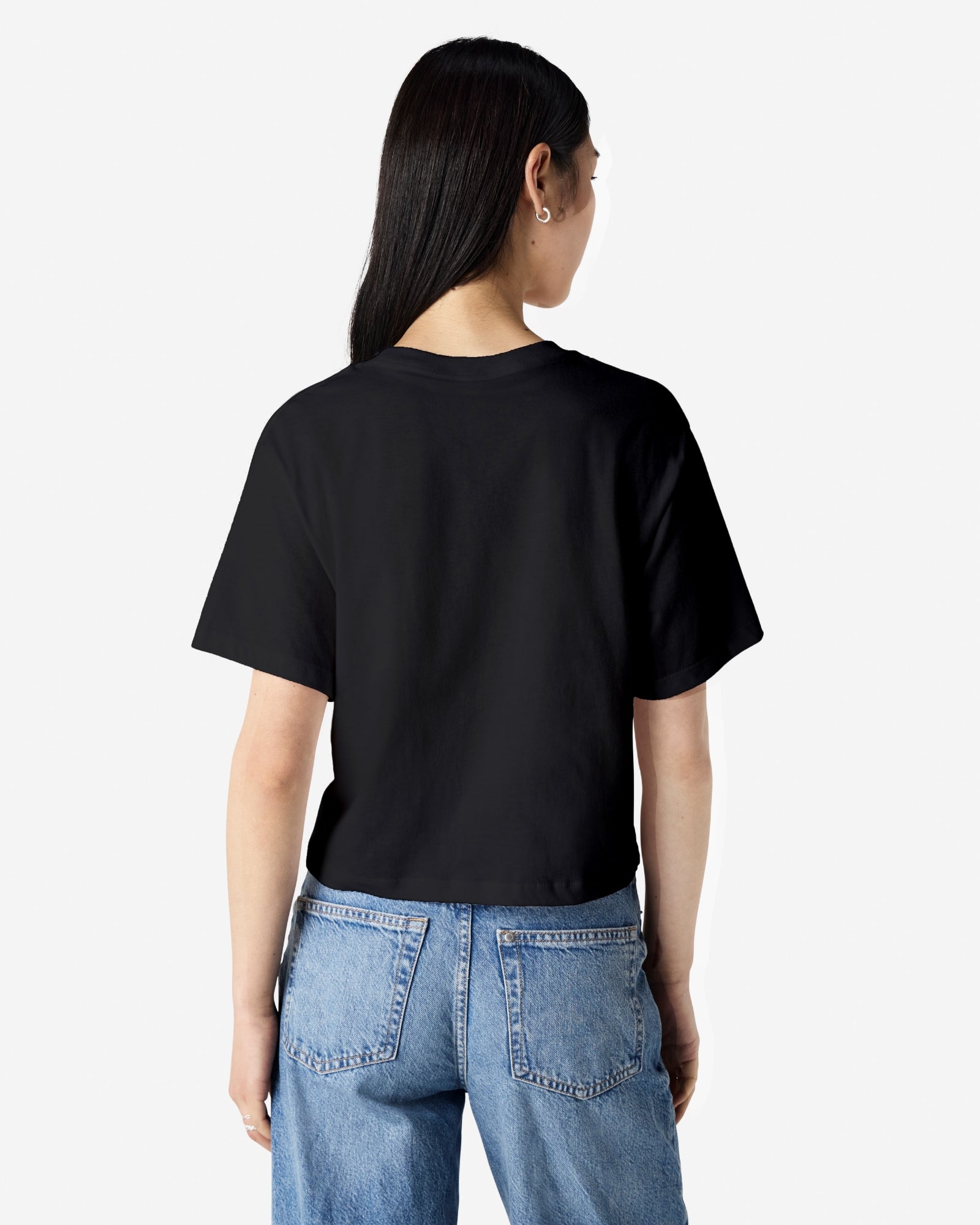 Female model wearing an American Apparel Fine Jersey Women's Boxy Tee in Black, paired with blue jeans, standing against a plain background (back pose) -black