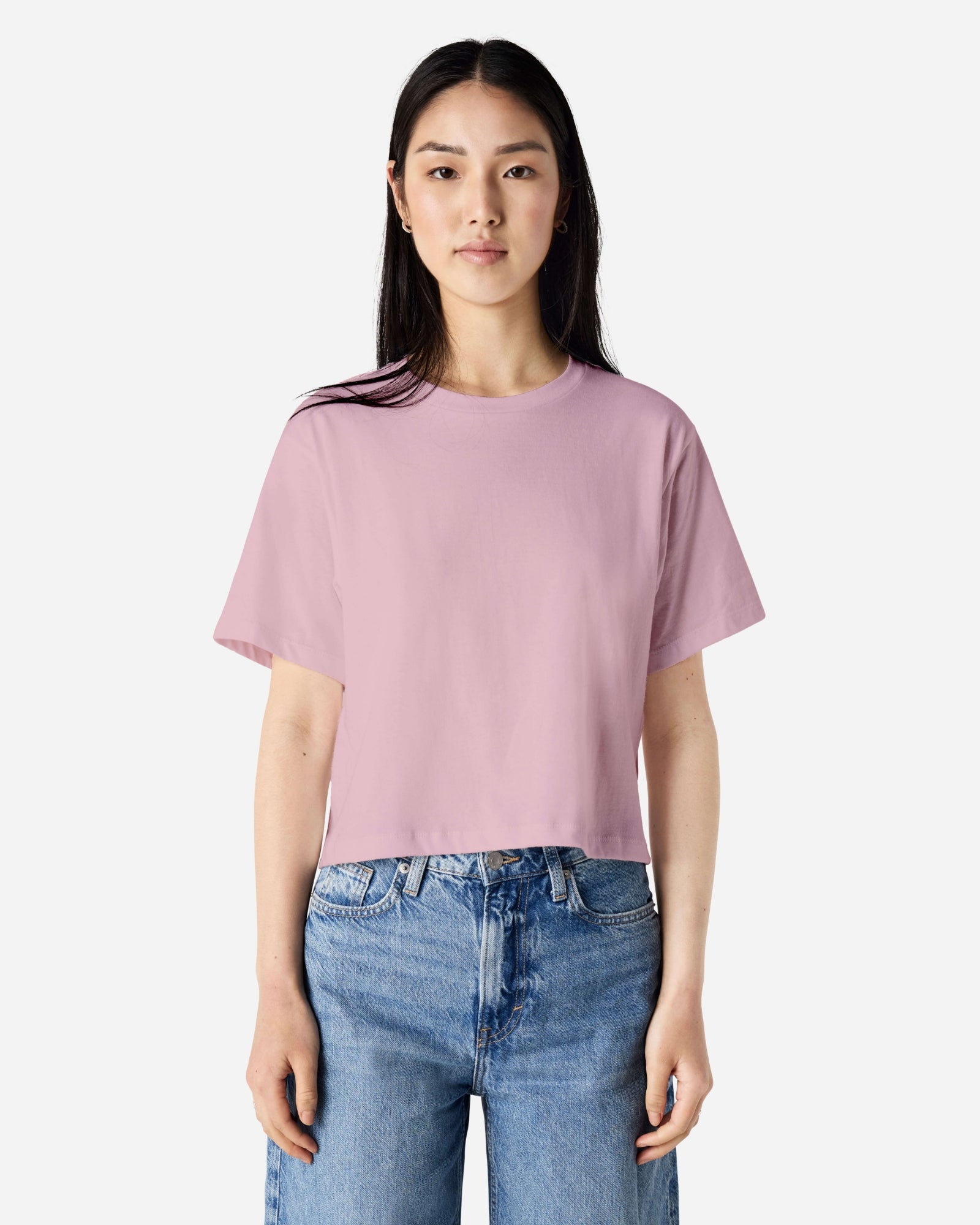 Female model wearing an American Apparel Fine Jersey Women's Boxy Tee in Blush, paired with blue jeans, standing against a plain background (front pose) -blush