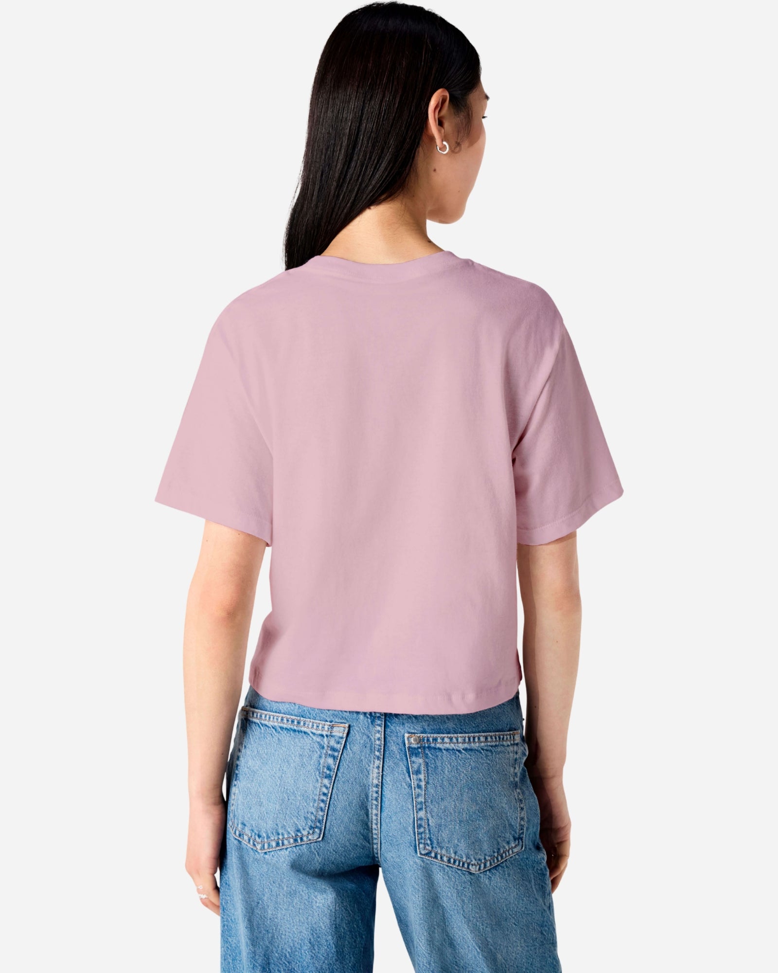 Female model wearing an American Apparel Fine Jersey Women's Boxy Tee in Blush, paired with blue jeans, standing against a plain background (back pose) -blush