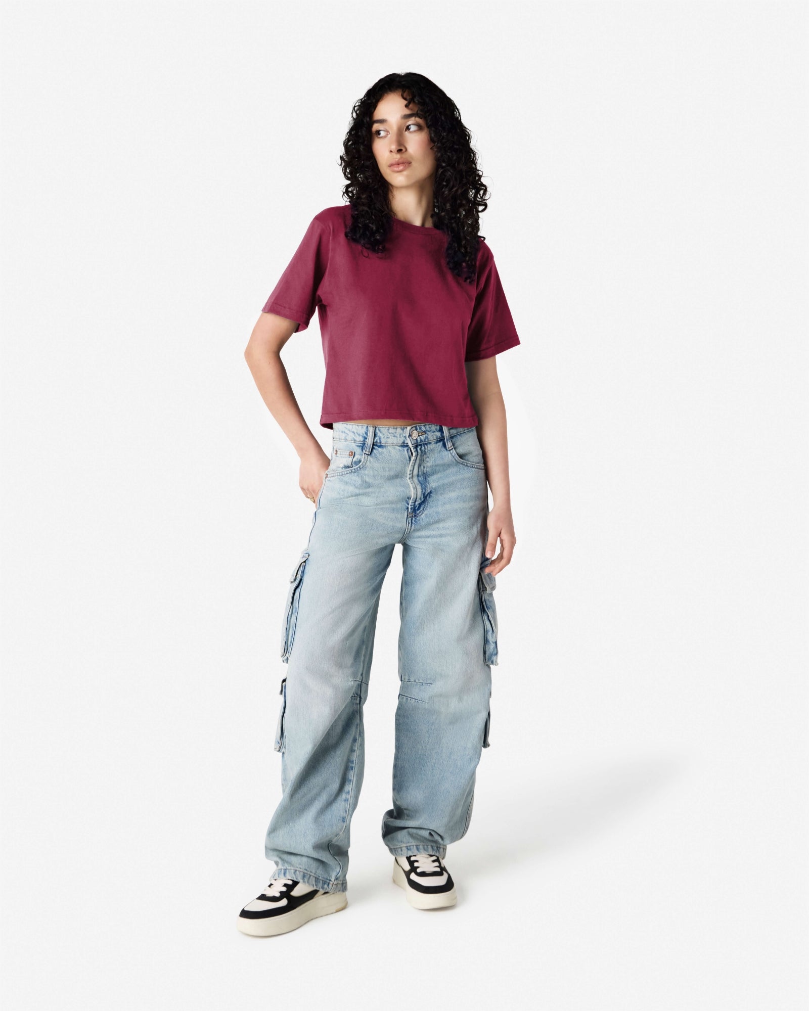 Female model wearing an American Apparel Fine Jersey Women's Boxy Tee in Burgundy, paired with blue jeans, standing against a plain background (front pose) -burgundy