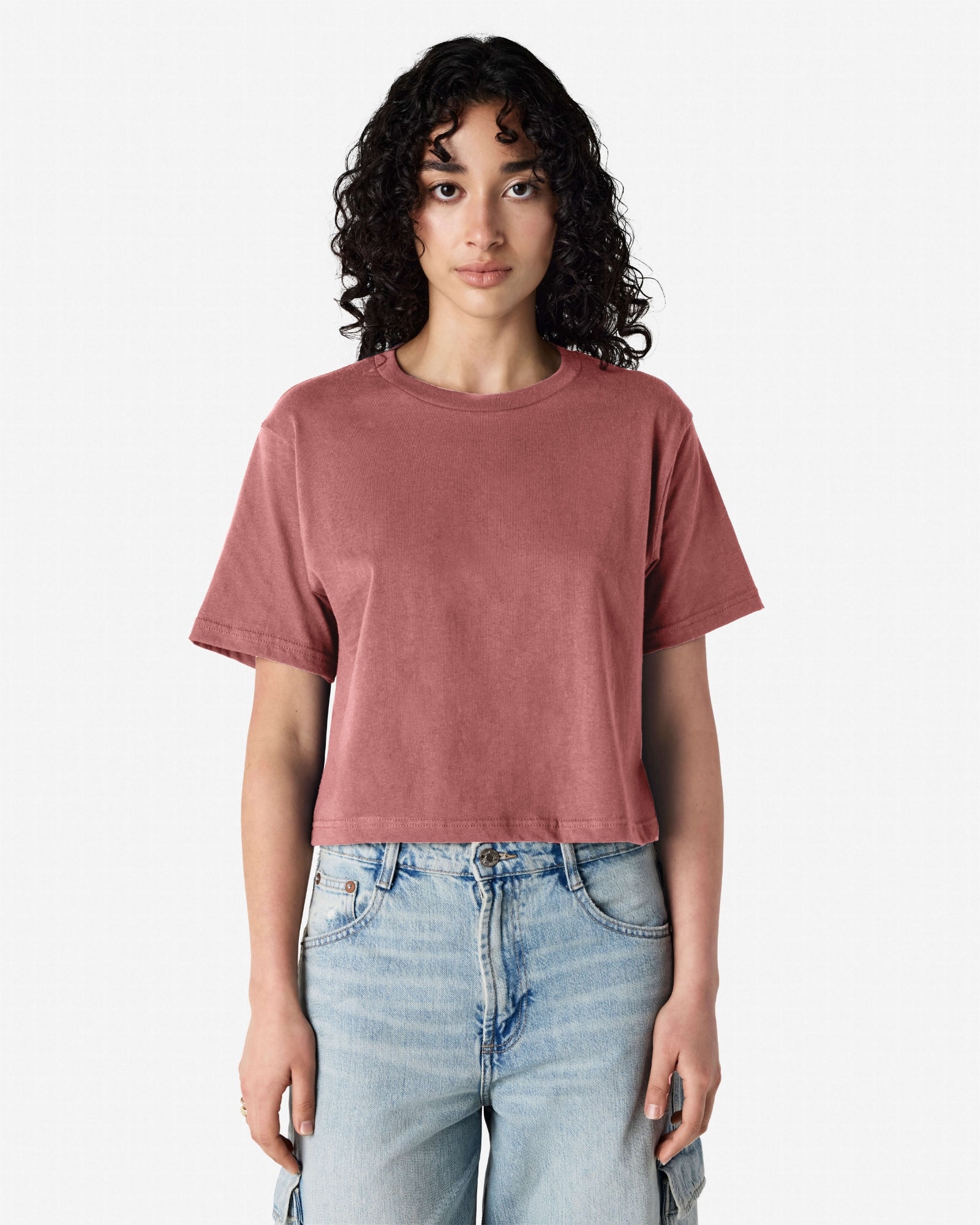 Female model wearing an American Apparel Fine Jersey Women's Boxy Tee in Canyon, paired with blue jeans, standing against a plain background (front pose) -canyon