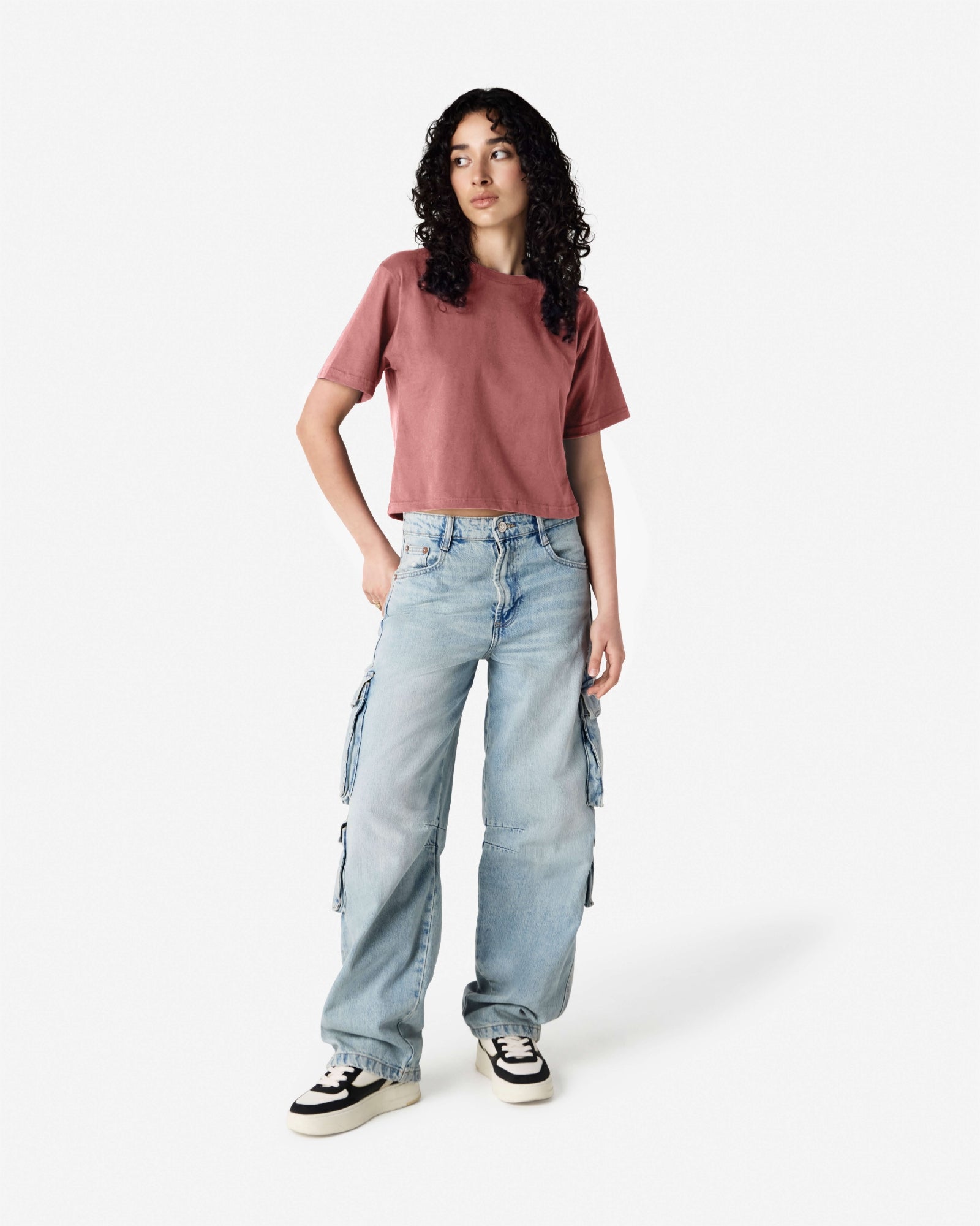 Female model wearing an American Apparel Fine Jersey Women's Boxy Tee in Canyon, paired with blue jeans, standing against a plain background (front pose) -canyon