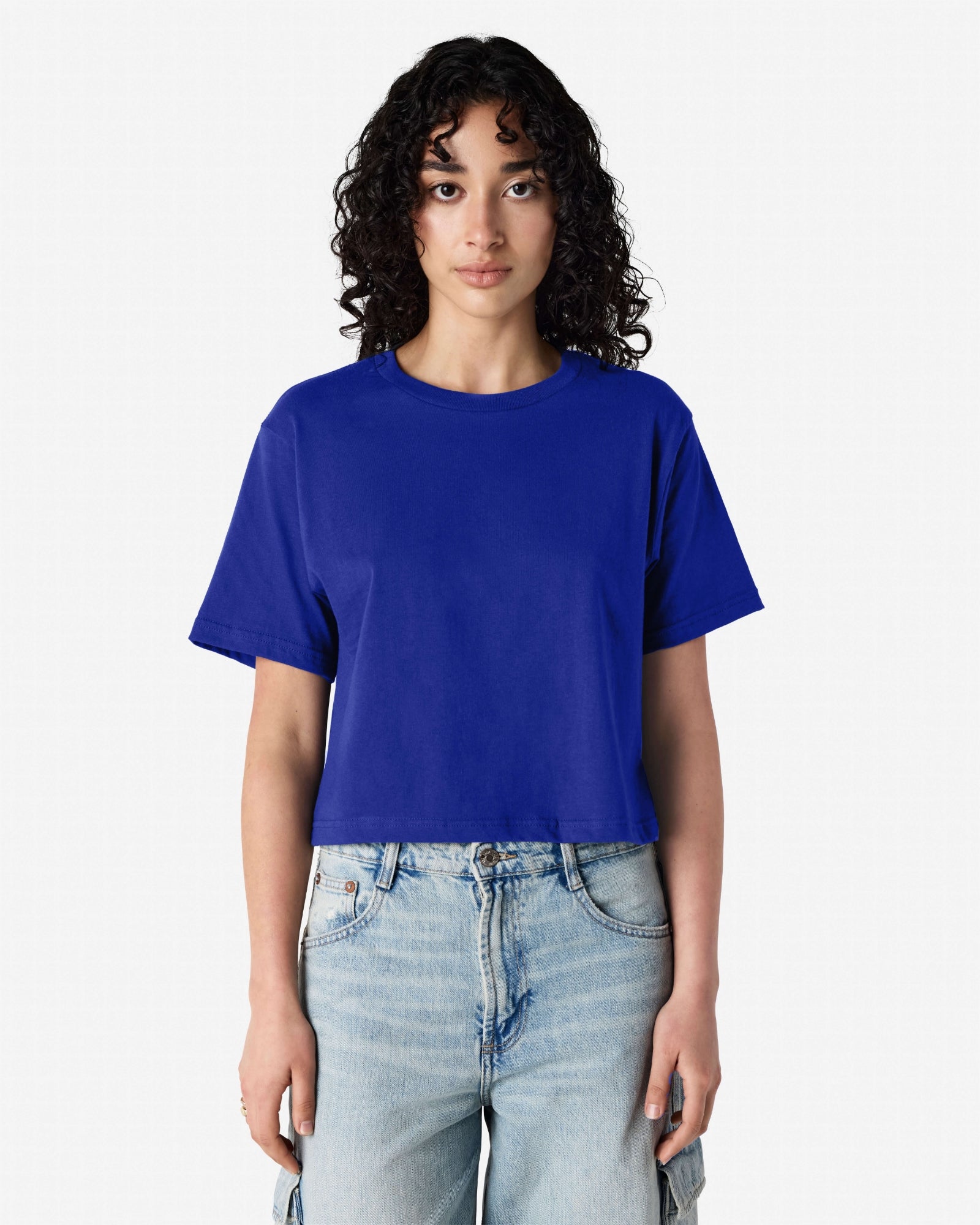 Female model wearing an American Apparel Fine Jersey Women's Boxy Tee in Lapis, paired with blue jeans, standing against a plain background (front pose) -lapis