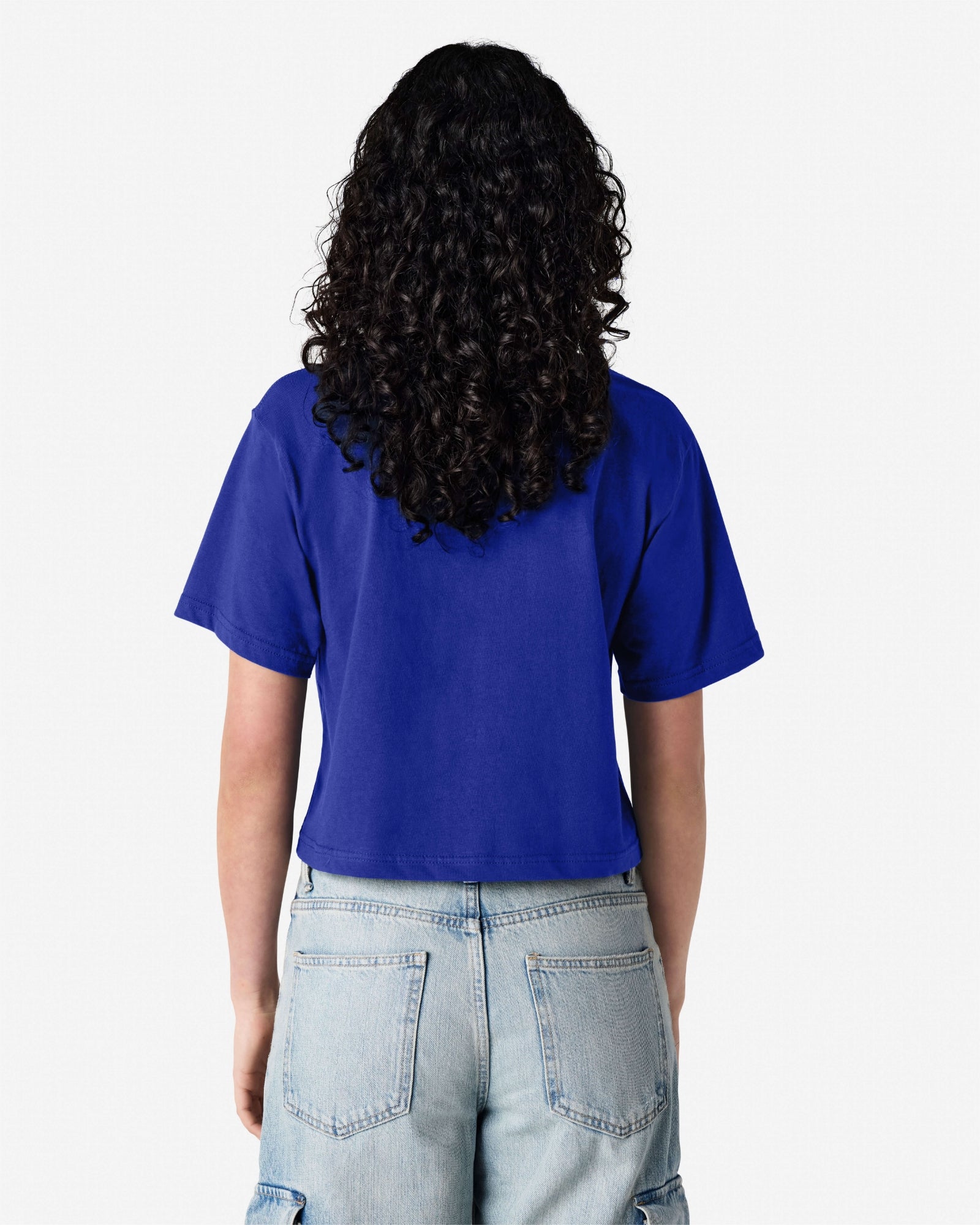 Female model wearing an American Apparel Fine Jersey Women's Boxy Tee in Lapis, paired with blue jeans, standing against a plain background (back pose) -lapis