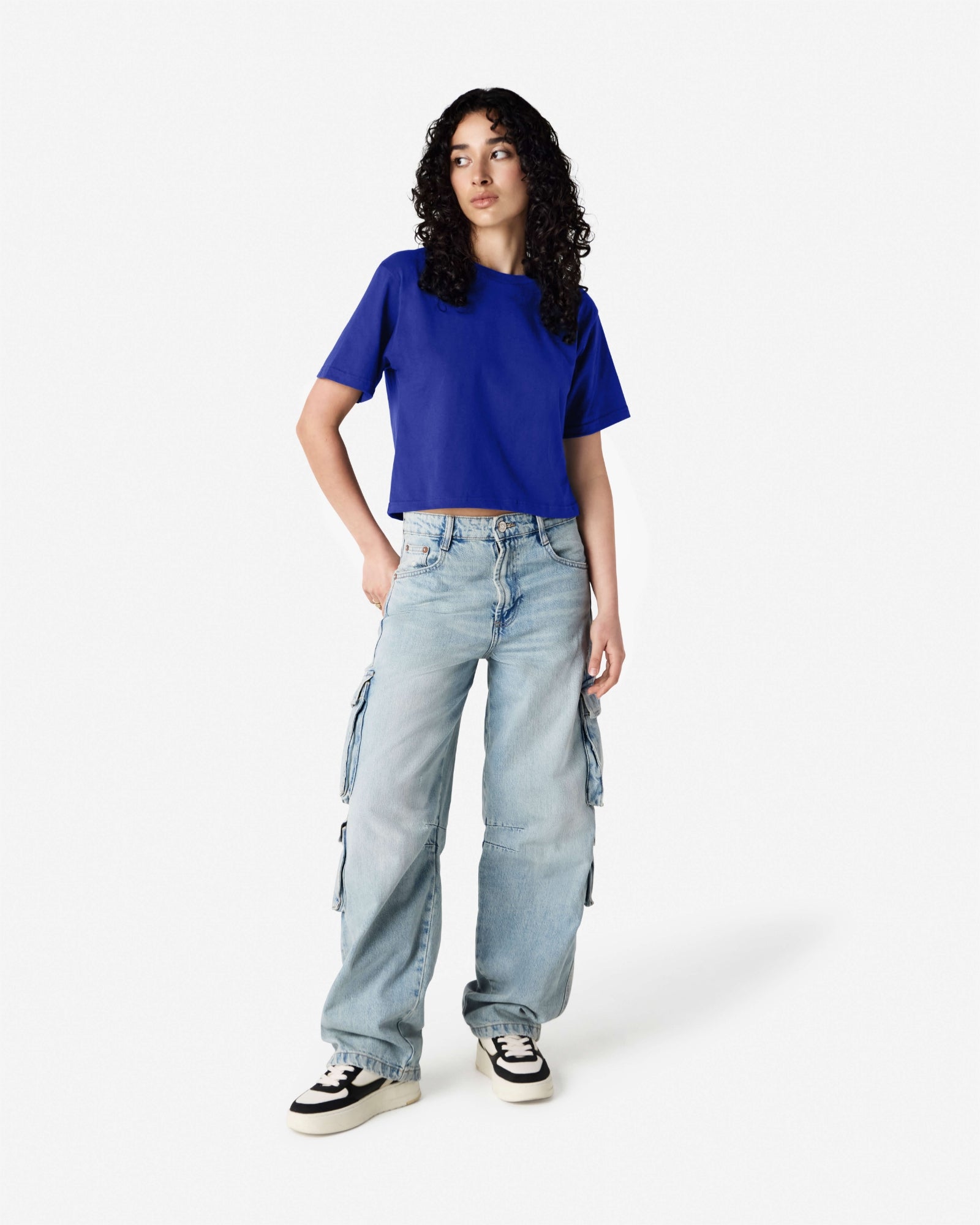 Female model wearing an American Apparel Fine Jersey Women's Boxy Tee in Lapis, paired with blue jeans, standing against a plain background (front pose) -lapis