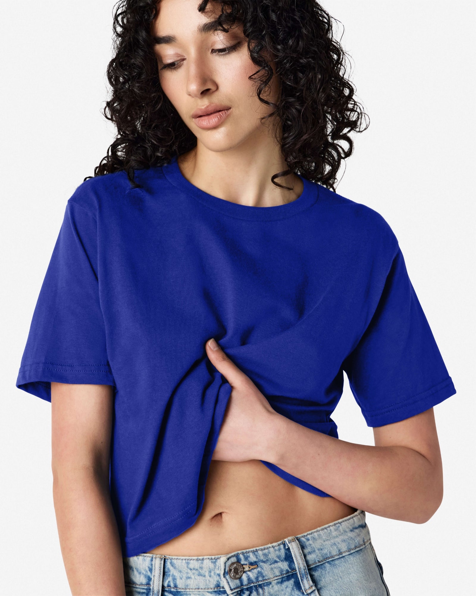 Female model wearing an American Apparel Fine Jersey Women's Boxy Tee in Lapis, paired with blue jeans, standing against a plain background (front pose) -lapis