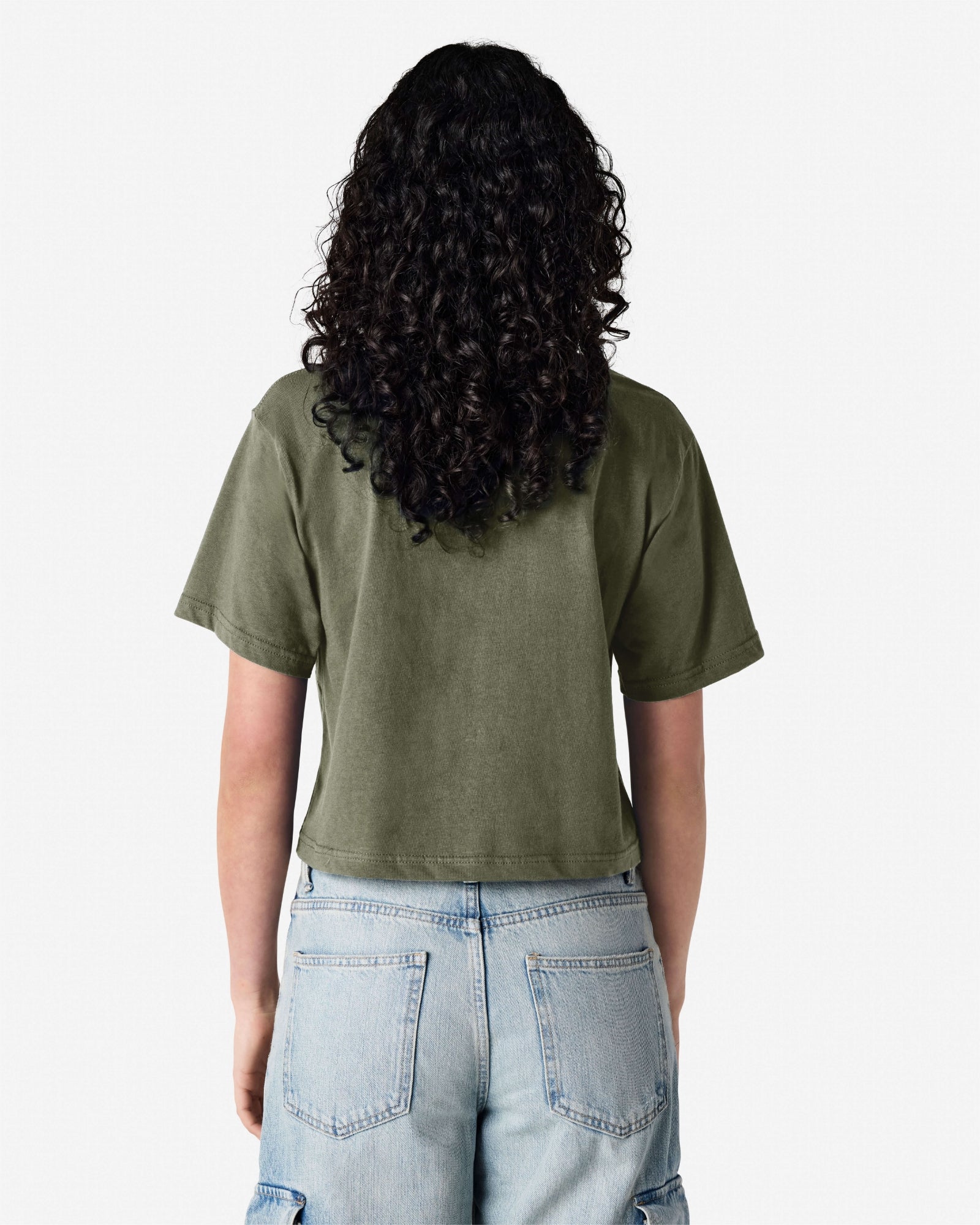 Female model wearing an American Apparel Fine Jersey Women's Boxy Tee in Liuetenant, paired with blue jeans, standing against a plain background (back pose) -liuetenant