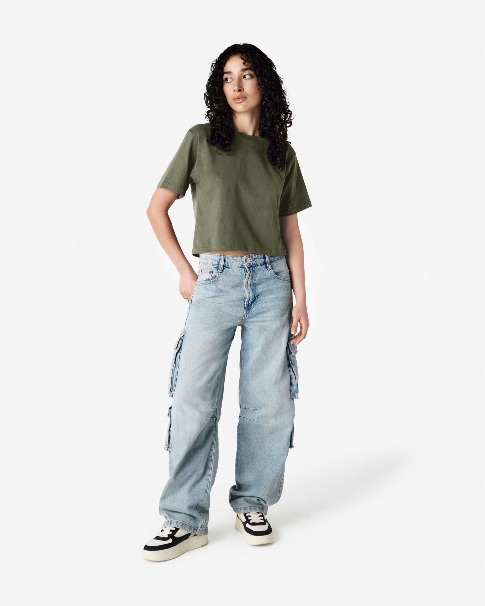 Female model wearing an American Apparel Fine Jersey Women's Boxy Tee in Liuetenant, paired with blue jeans, standing against a plain background (front pose) -liuetenant