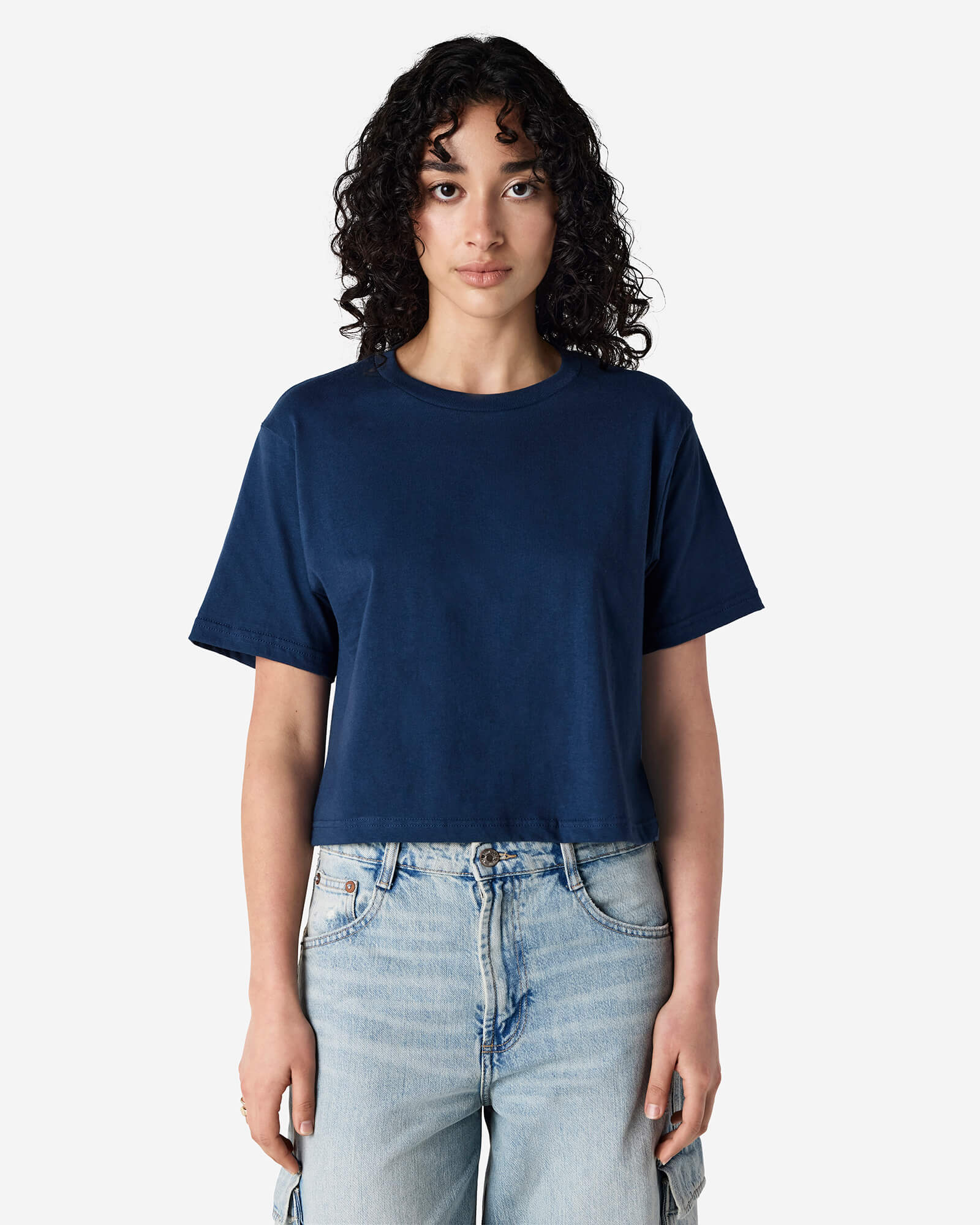 Female model wearing an American Apparel Fine Jersey Women's Boxy Tee in Sea Blue, paired with blue jeans, standing against a plain background (front pose) -sea blue