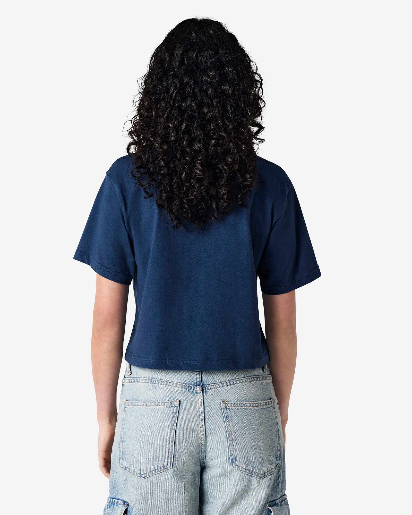 Female model wearing an American Apparel Fine Jersey Women's Boxy Tee in Sea Blue, paired with blue jeans, standing against a plain background (back pose) -sea blue