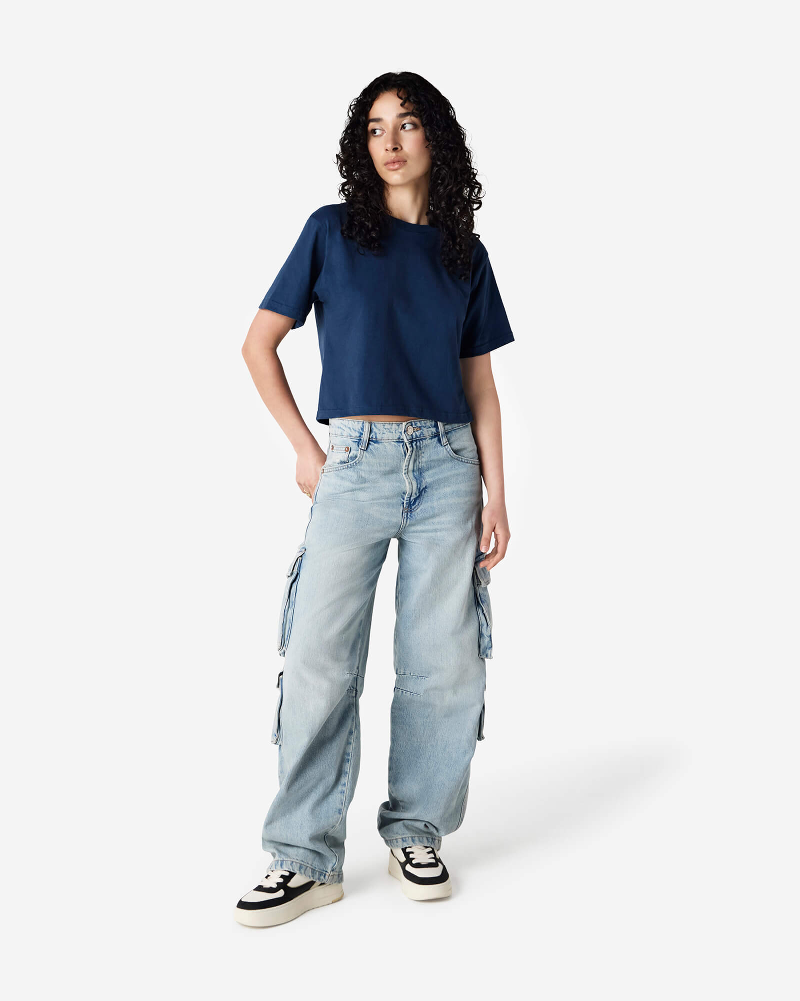 Female model wearing an American Apparel Fine Jersey Women's Boxy Tee in Sea Blue, paired with blue jeans, standing against a plain background (front pose) -sea blue