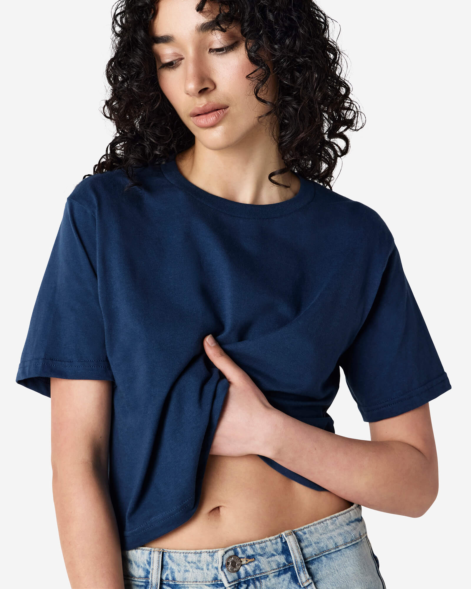 Female model wearing an American Apparel Fine Jersey Women's Boxy Tee in Sea Blue, paired with blue jeans, standing against a plain background (front pose) -sea blue