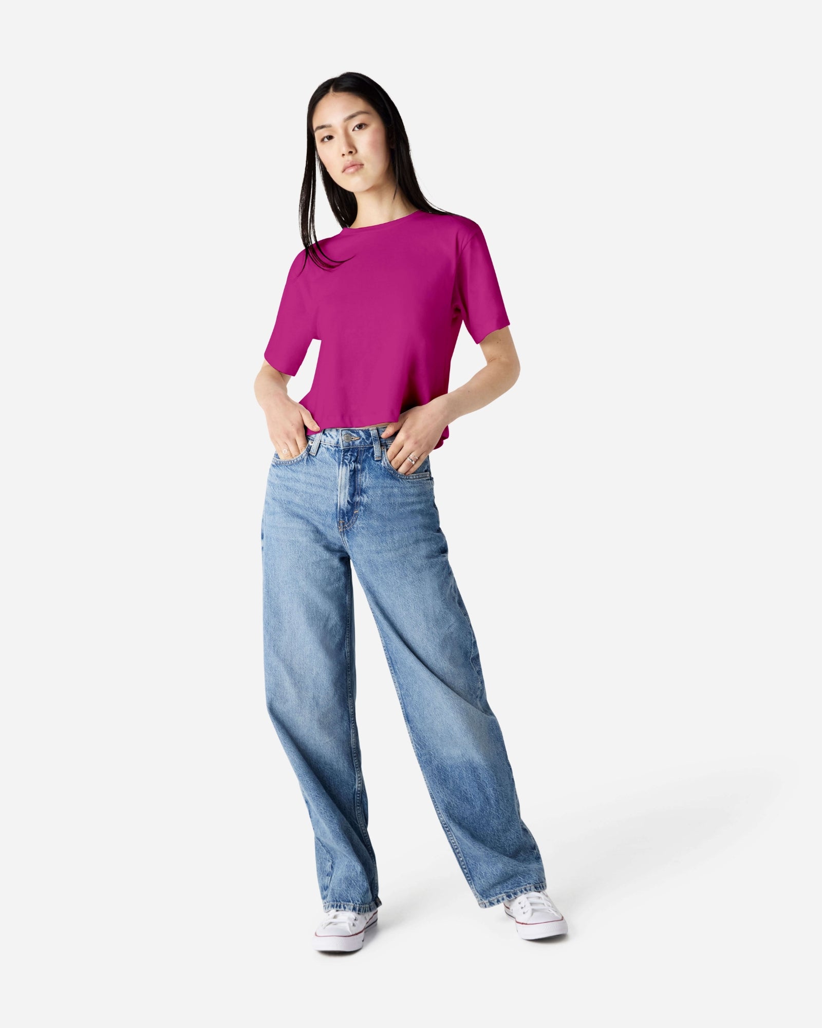 Female model wearing an American Apparel Fine Jersey Women's Boxy Tee in Super Pink, paired with blue jeans, standing against a plain background (front pose) -super pink