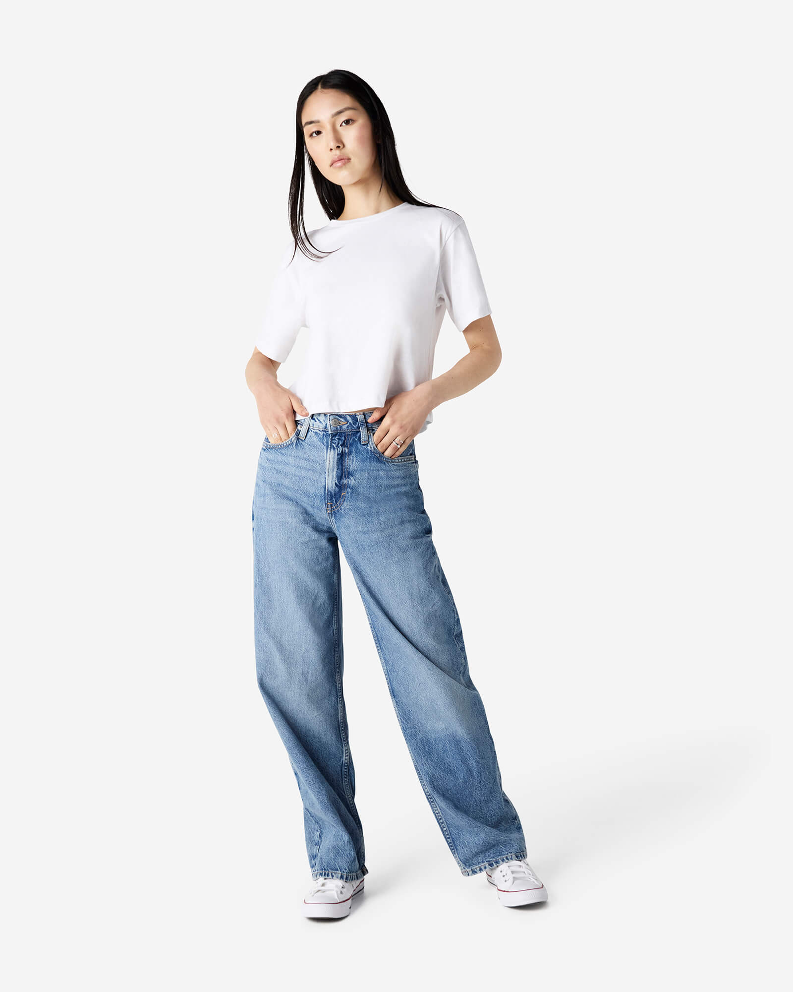 Female model wearing an American Apparel Fine Jersey Women's Boxy Tee in White, paired with blue jeans, standing against a plain background (front pose) -white