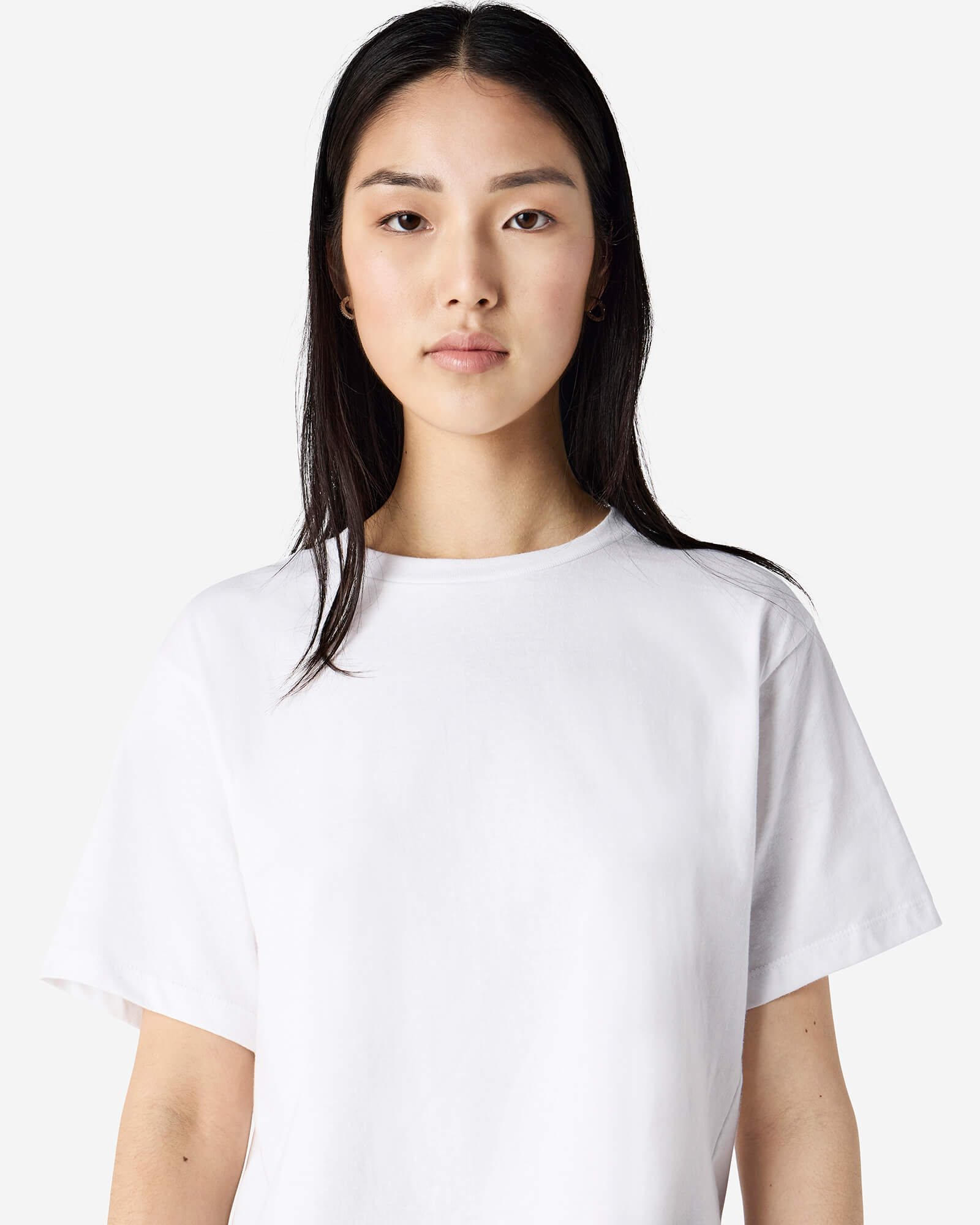 Female model wearing an American Apparel Fine Jersey Women's Boxy Tee in White, paired with blue jeans, standing against a plain background (front pose) -white