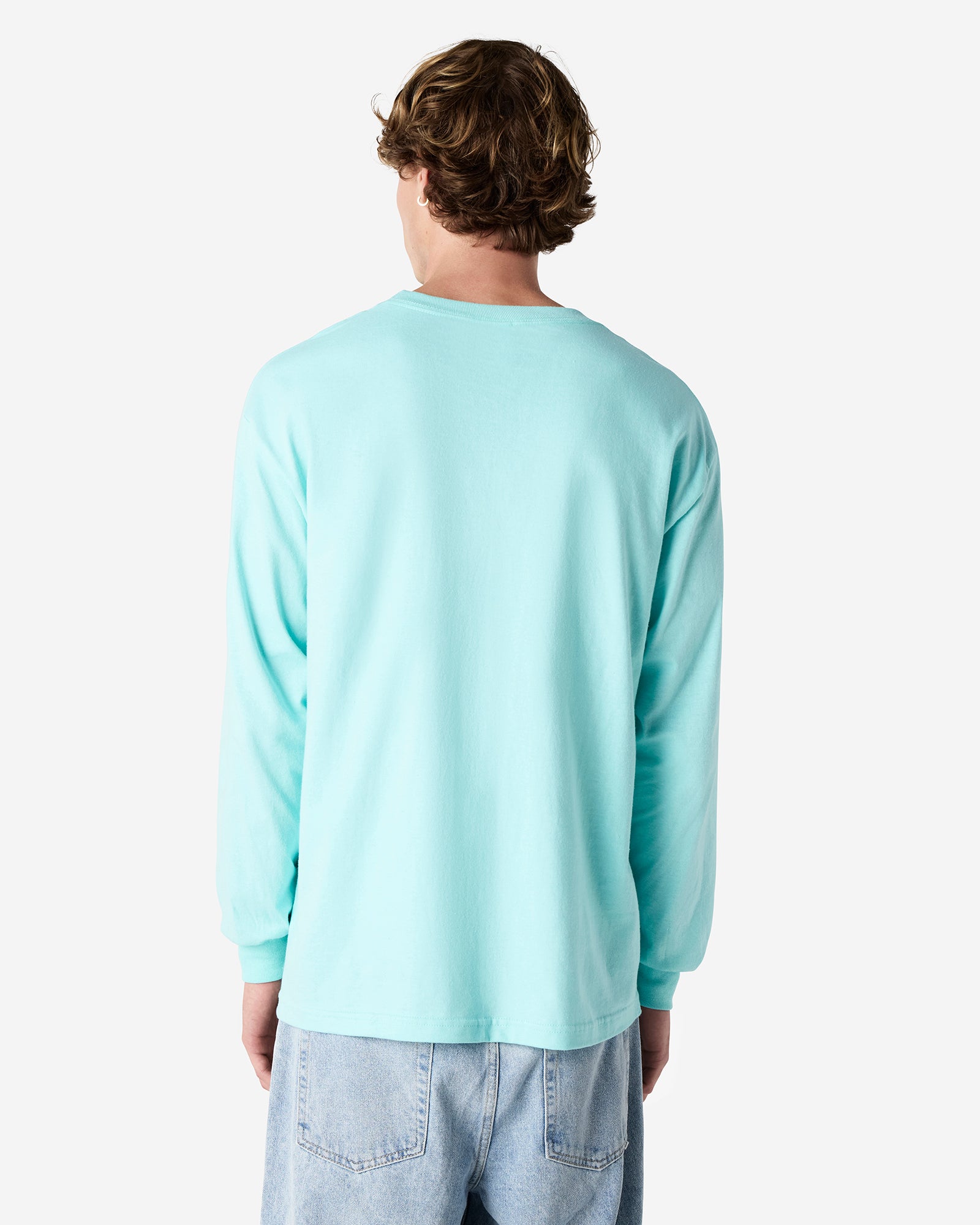 front view of a male Model wearing a Celadon colored Heavyweight Unisex Long Sleeve Crew Neck Tee, paired with blue jeans, standing against a plain background (back pose) -celadon