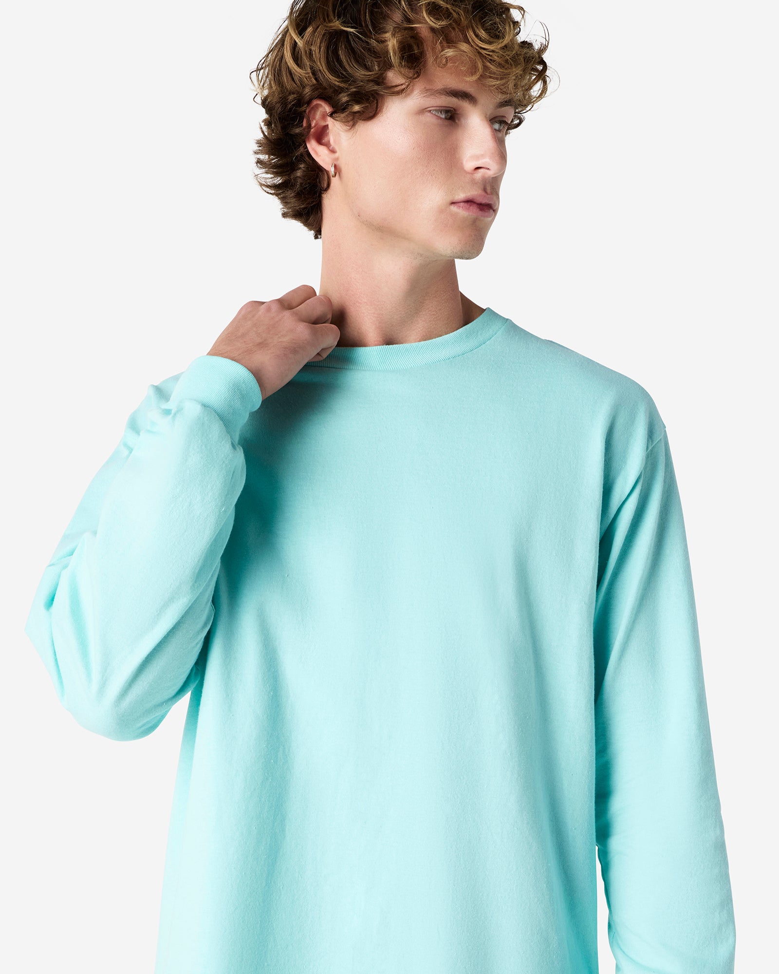 front view of a male Model wearing a Celadon colored Heavyweight Unisex Long Sleeve Crew Neck Tee, paired with blue jeans, standing against a plain background (front pose) -celadon