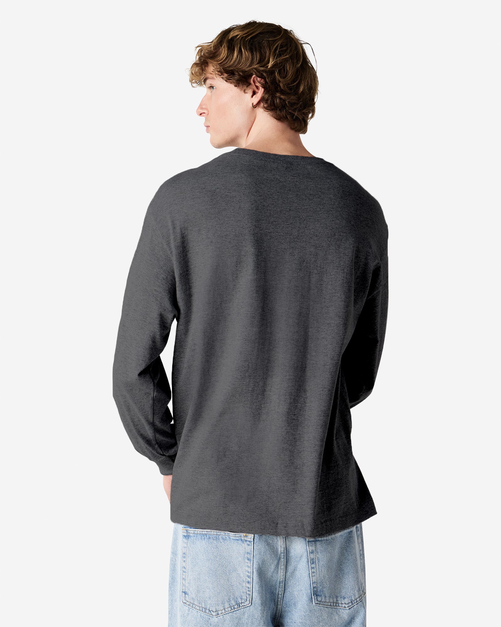 front view of a male Model wearing a Heather Charcoal colored Heavyweight Unisex Long Sleeve Crew Neck Tee, paired with blue jeans, standing against a plain background (back pose) -heather charcoal