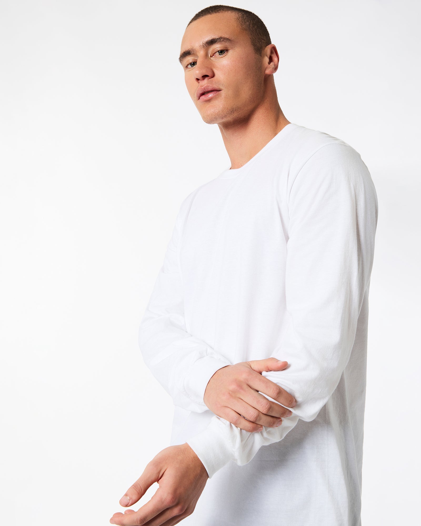 male model wearing American Apparel white Colour Fine Jersey Unisex Long Sleeve Crew Neck T-shirt- hand on wrist Front pose