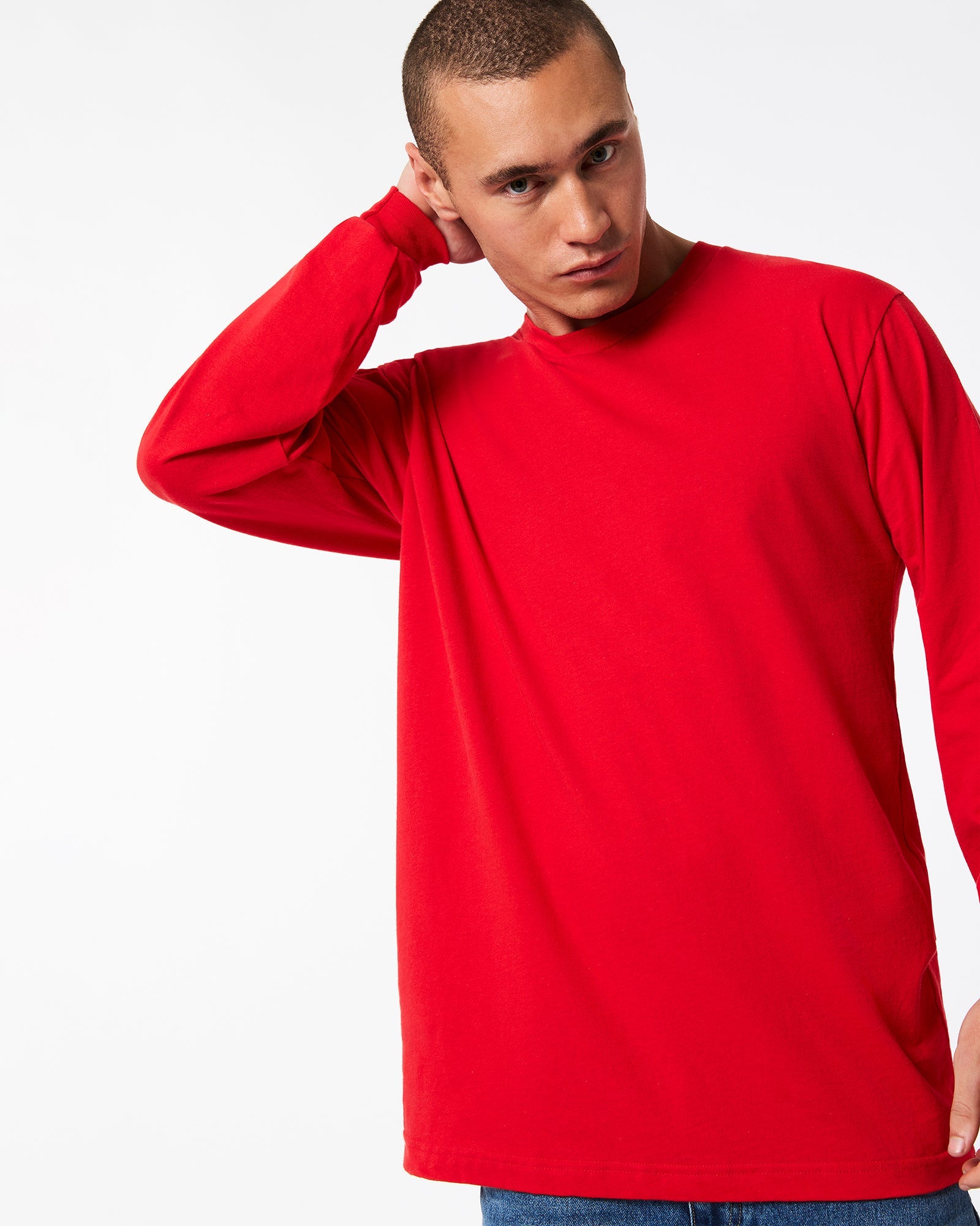 male model wearing American Apparel Red Colour Fine Jersey Unisex Long Sleeve Crew Neck T-shirt- hand behind head pose